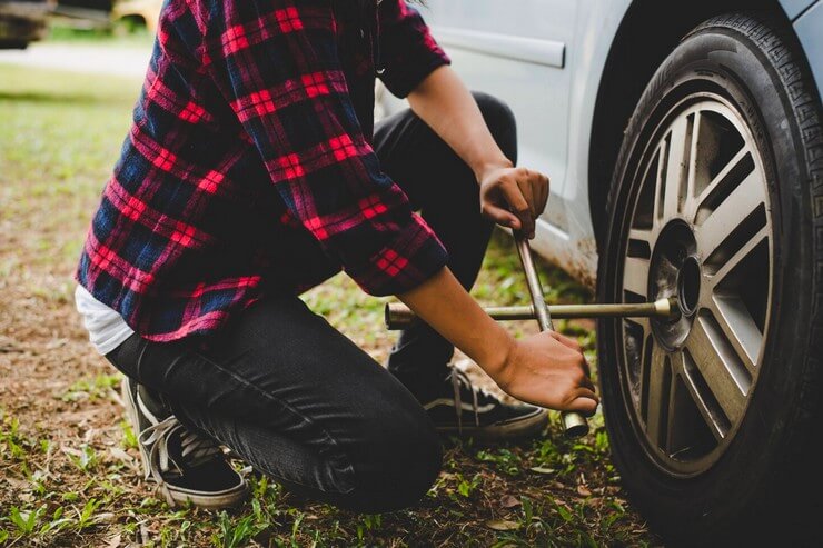 Jeune homme qui change une roue de voiture